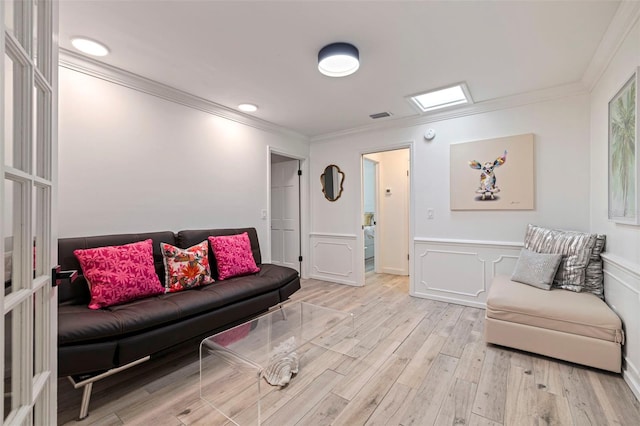 living area featuring crown molding, visible vents, wainscoting, and light wood-style floors