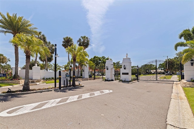 view of road with street lighting, a gated entry, a gate, and curbs