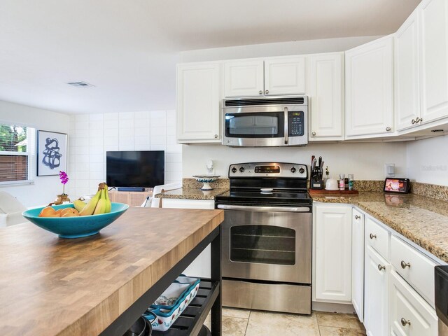 1700 25th St N, Saint Petersburg, FL 33713 - kitchen featuring visible vents, light stone countertops, white cabinetry, light tile patterned floors, and stainless steel appliances