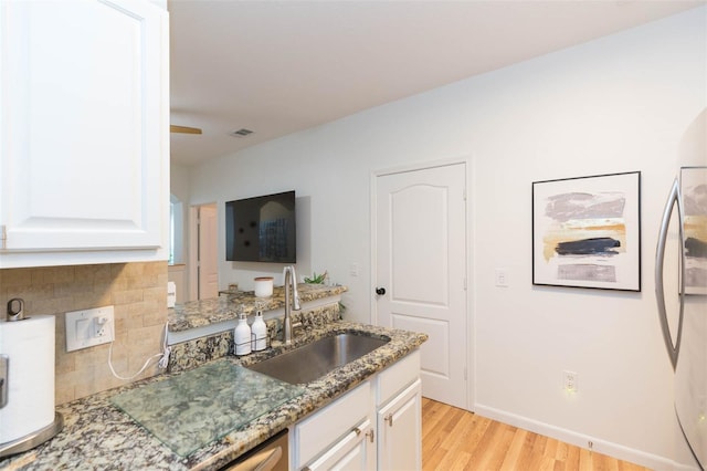 10473 Villa View Cir, Tampa, FL 33647 - kitchen featuring white cabinets, a sink, light wood-style floors, stone counters, and backsplash