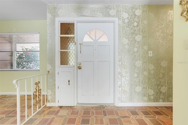entrance foyer featuring baseboards and wallpapered walls
