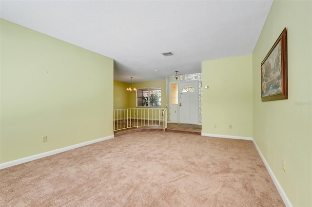 unfurnished room with baseboards, a notable chandelier, carpet flooring, and visible vents