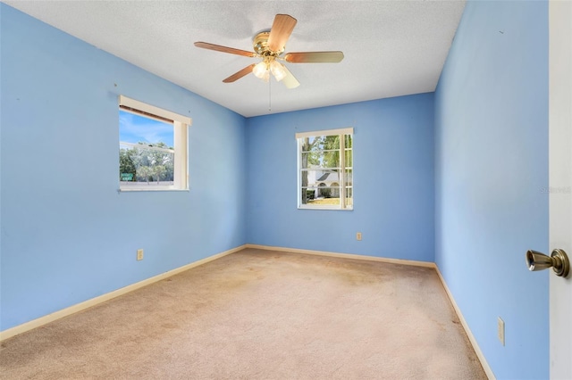 carpeted spare room with baseboards, a ceiling fan, and a textured ceiling