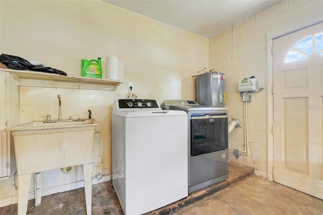 clothes washing area featuring separate washer and dryer, laundry area, water heater, and concrete block wall
