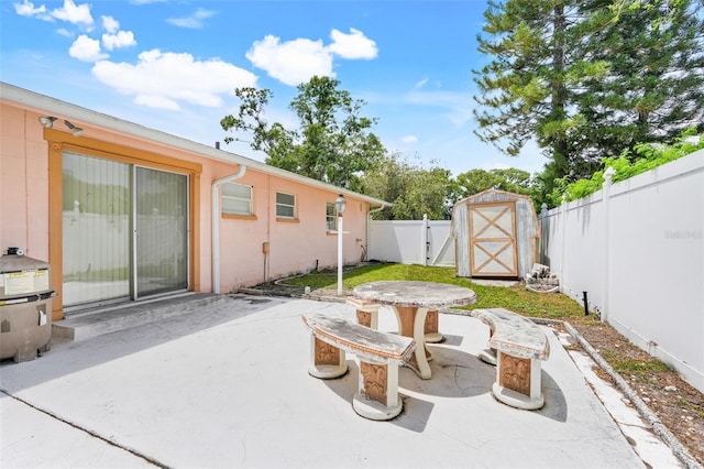 view of patio featuring a gate, a fenced backyard, and a shed