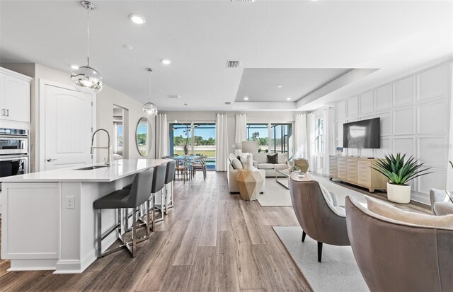 17085 Moonflower Dr, Venice, FL 34293 - interior space with light wood-style flooring, a sink, white cabinetry, visible vents, and open floor plan