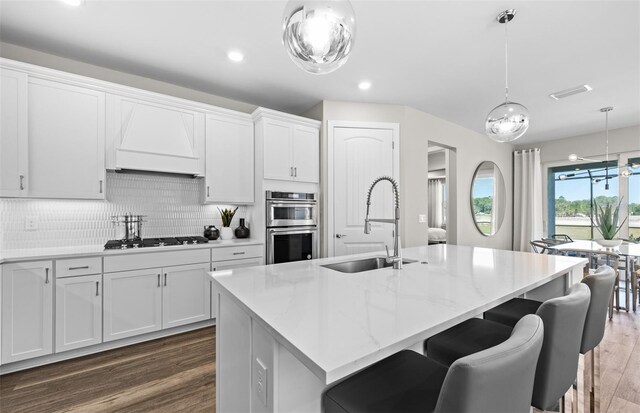 17085 Moonflower Dr, Venice, FL 34293 - kitchen with double oven, dark wood-style flooring, a sink, visible vents, and premium range hood