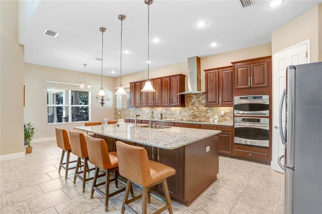 3243 Watermark Dr, Wesley Chapel, FL 33544 - kitchen with a sink, freestanding refrigerator, wall chimney exhaust hood, a kitchen island with sink, and backsplash