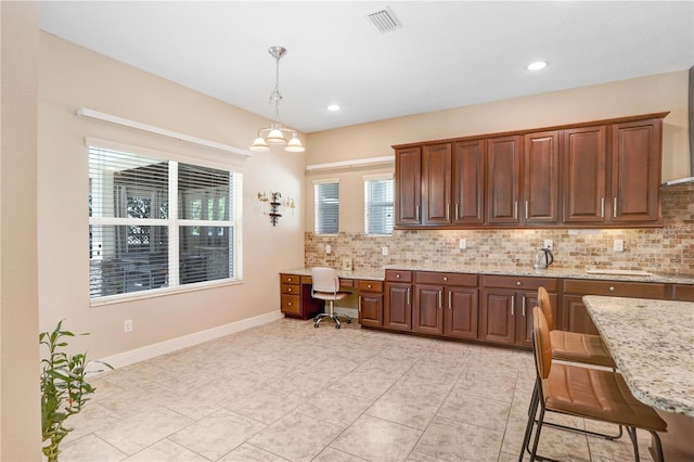 3243 Watermark Dr, Wesley Chapel, FL 33544 - kitchen with hanging light fixtures, light stone countertops, light tile patterned flooring, and decorative backsplash