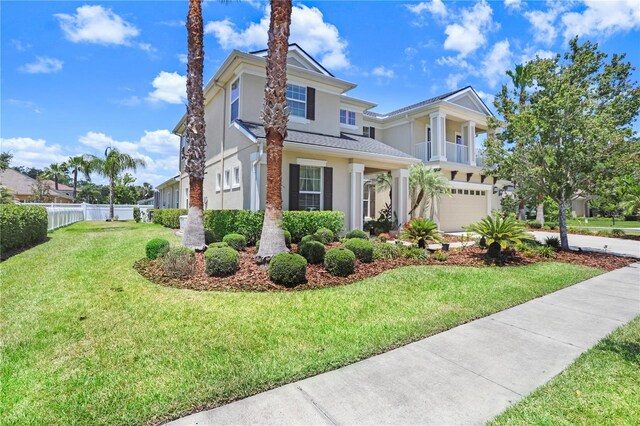 3243 Watermark Dr, Wesley Chapel, FL 33544 - view of front of house featuring an attached garage, stucco siding, fence, a front yard, and a balcony