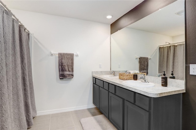 bathroom with a sink, tile patterned flooring, double vanity, and baseboards