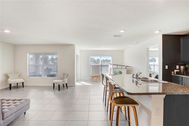 kitchen featuring a breakfast bar, a sink, open floor plan, visible vents, and light tile patterned flooring