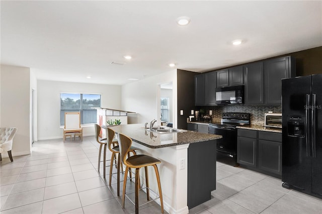 kitchen with dark cabinetry, black appliances, a sink, and a kitchen bar