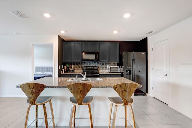 kitchen with a breakfast bar area, visible vents, black appliances, and a sink