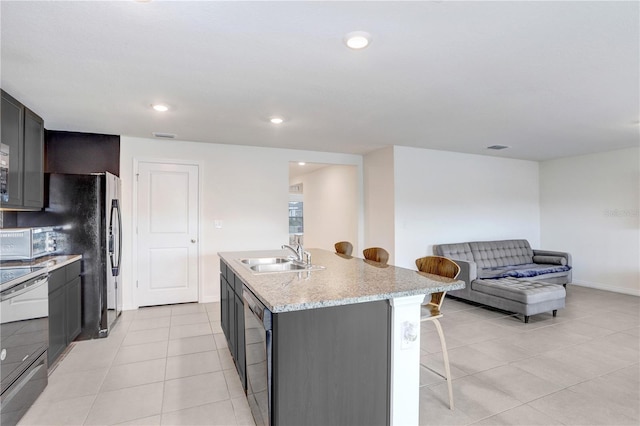 kitchen with light tile patterned floors, stainless steel electric range, a sink, a kitchen bar, and dishwashing machine