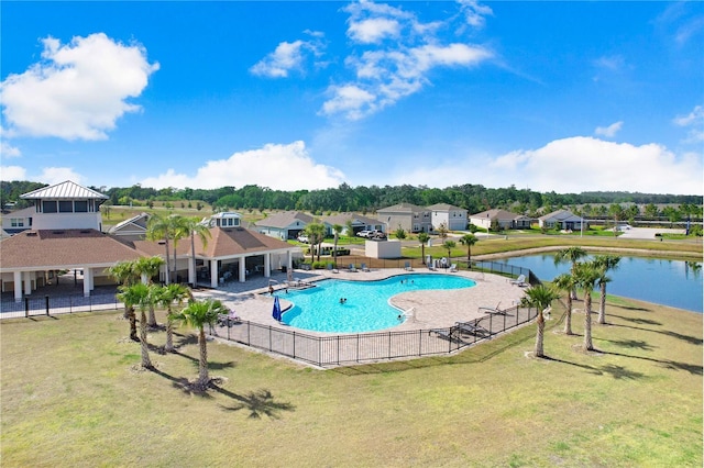 pool with a yard, fence, a water view, a patio area, and a residential view