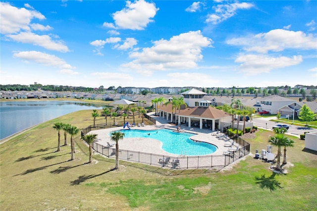 community pool featuring fence, a water view, and a residential view