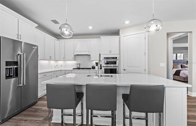 kitchen with stainless steel appliances, custom range hood, a sink, visible vents, and dark wood-type flooring