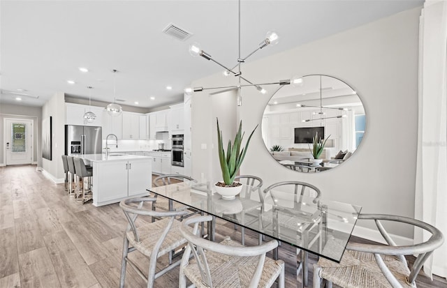 dining room with light wood finished floors, baseboards, visible vents, and recessed lighting