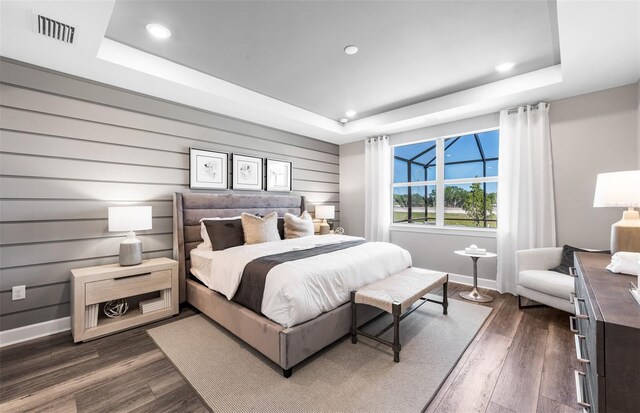 bedroom with visible vents, dark wood-style flooring, and a tray ceiling