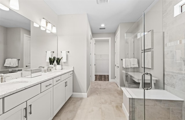 full bath with a spacious closet, double vanity, a sink, baseboards, and a stall shower