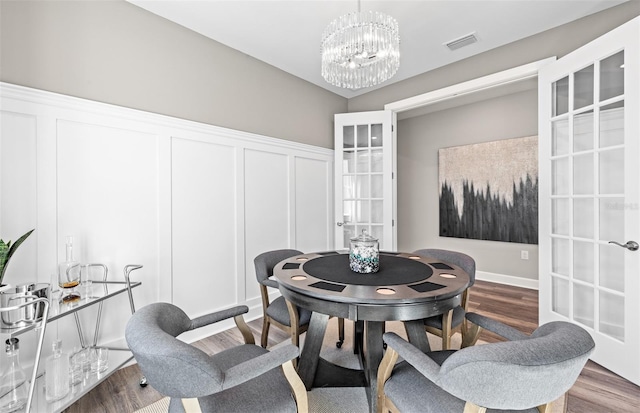 dining room featuring visible vents, wood finished floors, an inviting chandelier, and french doors