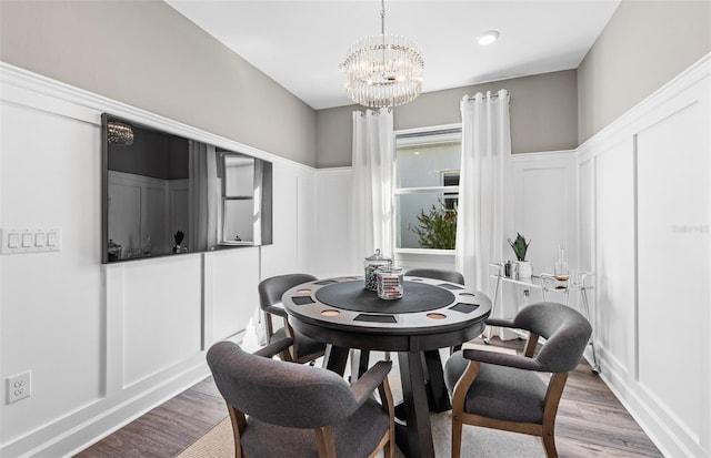 dining space with an inviting chandelier, wood finished floors, and a decorative wall