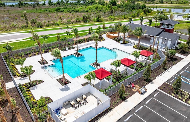 community pool featuring fence, a patio, and a water view