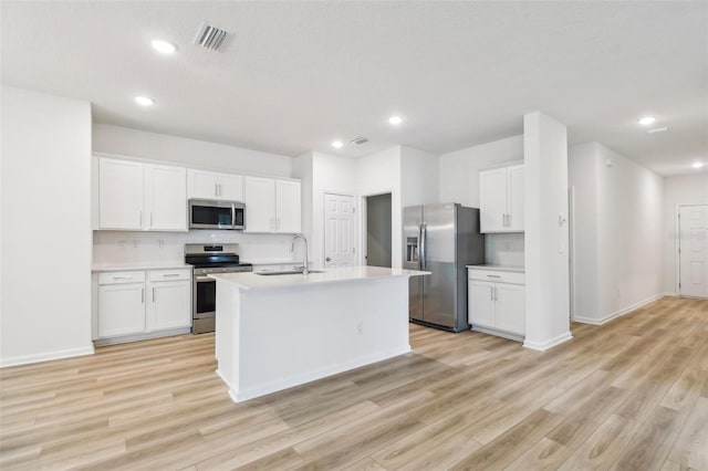 kitchen with a sink, stainless steel appliances, light wood-style flooring, light countertops, and white cabinets