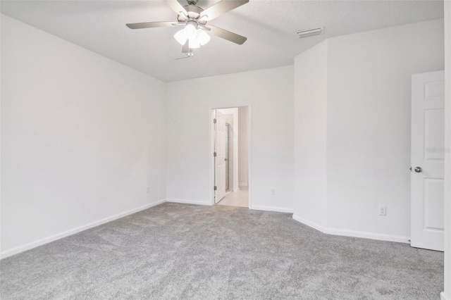 carpeted spare room featuring a ceiling fan, visible vents, and baseboards