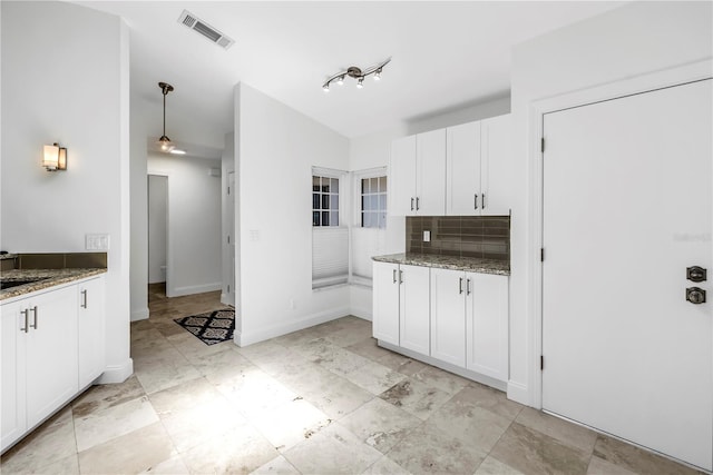kitchen with light stone counters, backsplash, white cabinetry, and visible vents
