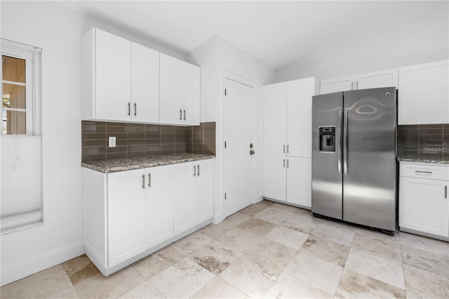kitchen with backsplash, light stone countertops, stainless steel fridge, and white cabinets