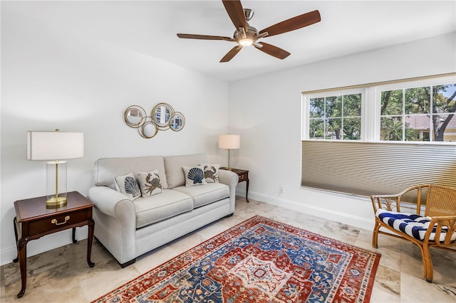 living area featuring a ceiling fan and baseboards