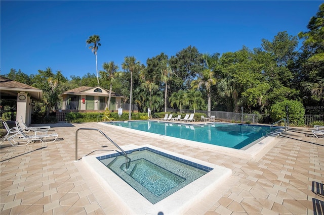 community pool with a patio, fence, and a community hot tub