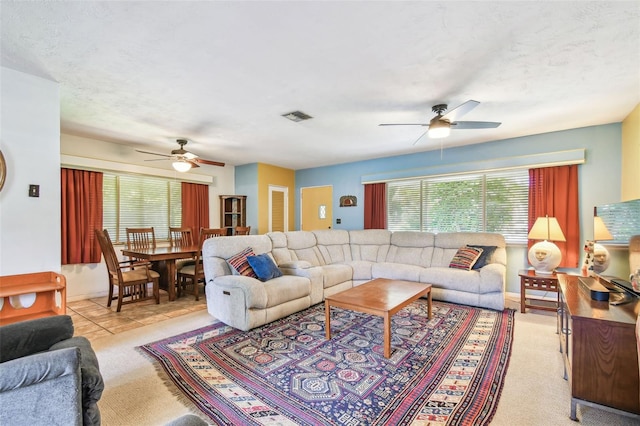 living area featuring ceiling fan, light carpet, a healthy amount of sunlight, and visible vents