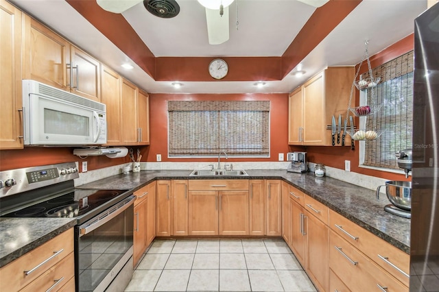 kitchen with dark stone counters, light tile patterned flooring, a sink, and stainless steel appliances