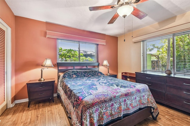 bedroom with ceiling fan, light wood-style flooring, and baseboards