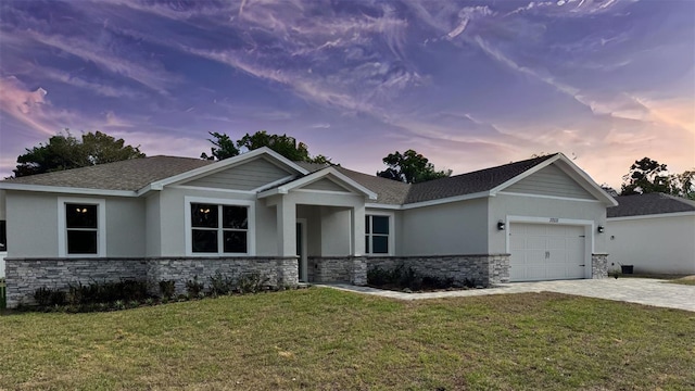 craftsman-style house featuring decorative driveway, a yard, stone siding, and an attached garage