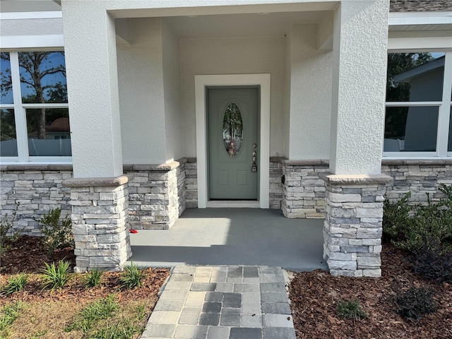 doorway to property featuring stucco siding and stone siding