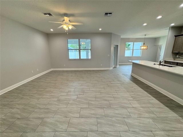 unfurnished living room with recessed lighting, a sink, baseboards, and visible vents