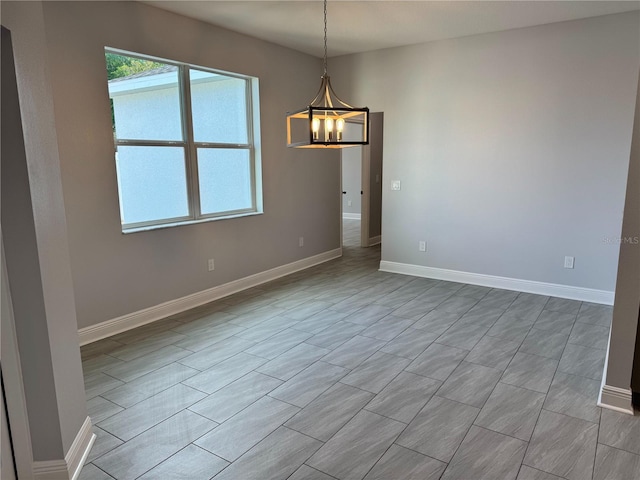 empty room with an inviting chandelier and baseboards