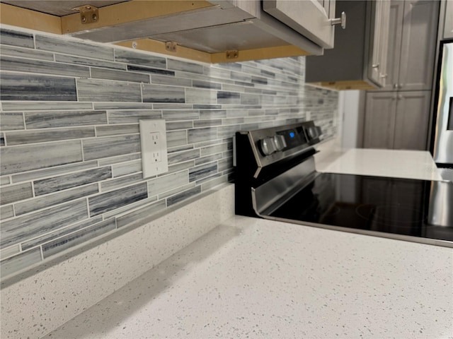 kitchen featuring light countertops, stainless steel electric stove, and tasteful backsplash
