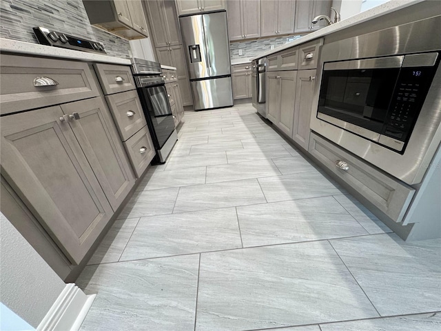 kitchen with gray cabinets, backsplash, appliances with stainless steel finishes, and light countertops