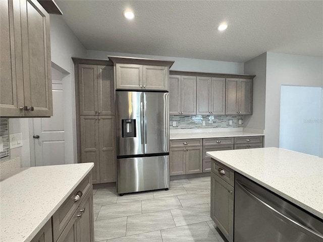 kitchen with recessed lighting, light stone countertops, appliances with stainless steel finishes, and decorative backsplash