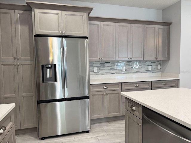 kitchen with gray cabinetry, stainless steel appliances, and tasteful backsplash