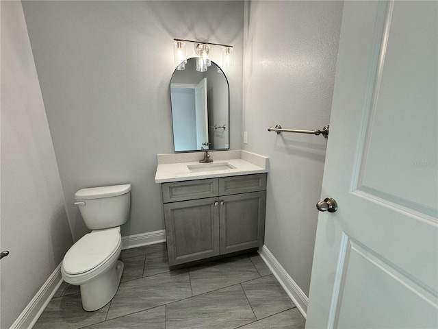 half bathroom featuring baseboards, toilet, and vanity