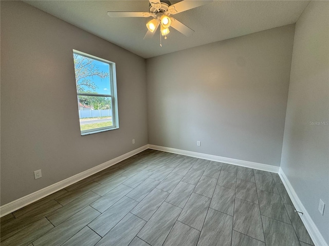 unfurnished room with wood tiled floor, a ceiling fan, and baseboards