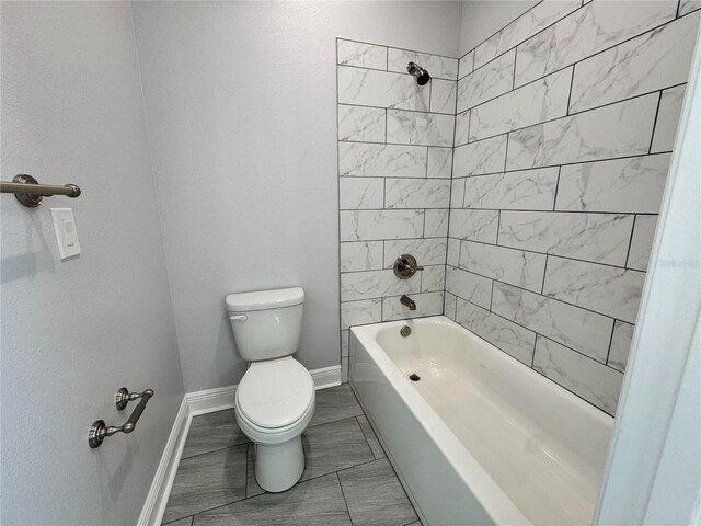 bathroom with toilet, bathing tub / shower combination, and baseboards
