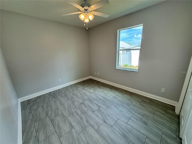 spare room featuring a ceiling fan and baseboards