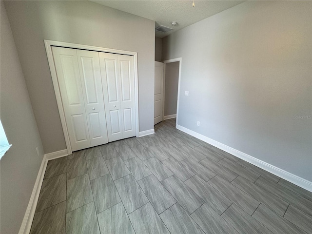 unfurnished bedroom featuring baseboards, a textured ceiling, and a closet